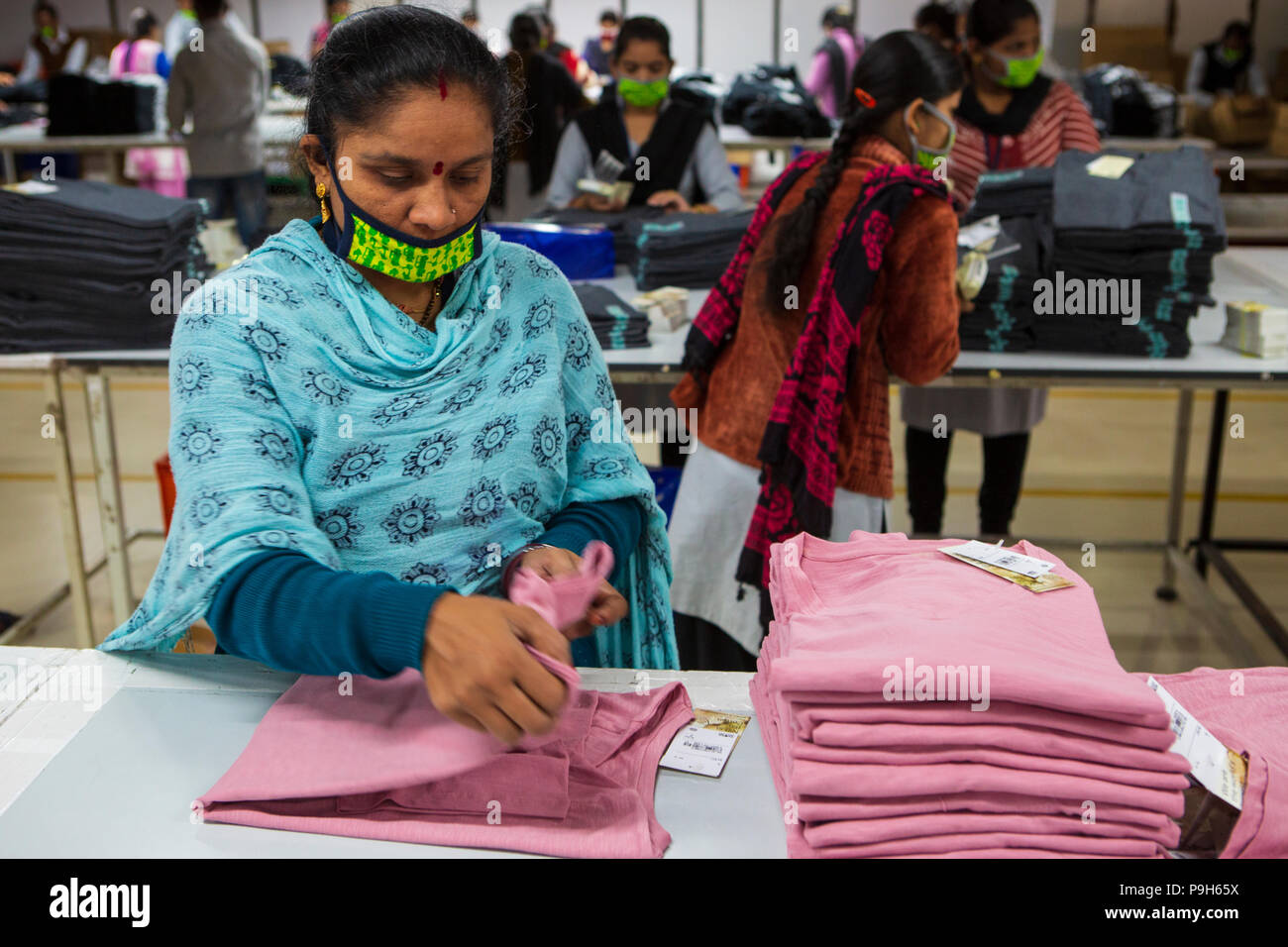 Frauen T-shirts Falten auf einer Produktionslinie in einer Textilfabrik, wo organische Baumwolle verwendet wird Kleidung zu machen, Indore, Indien. Stockfoto