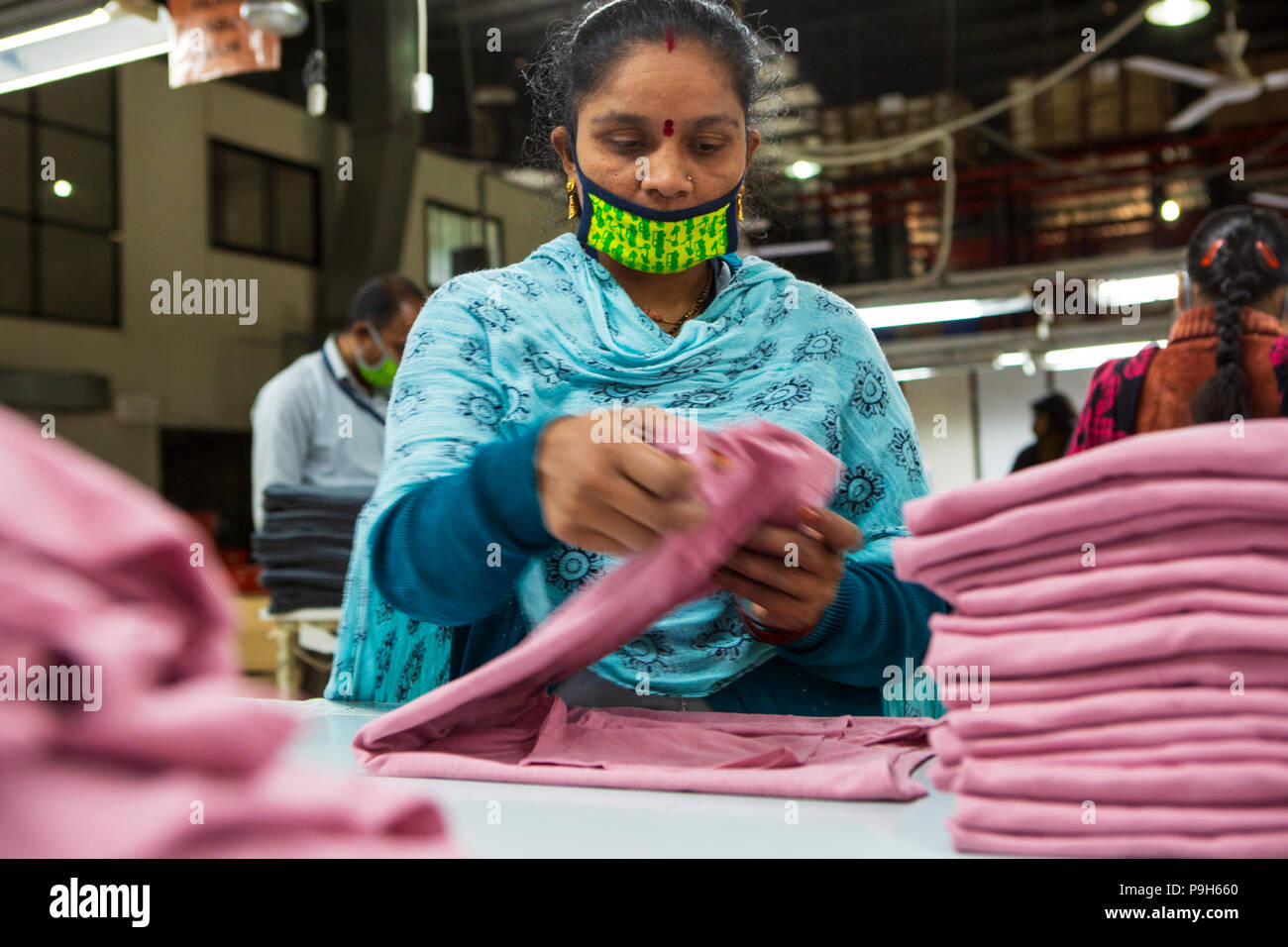 Frauen T-shirts Falten auf einer Produktionslinie in einer Textilfabrik, wo organische Baumwolle verwendet wird Kleidung zu machen, Indore, Indien. Stockfoto
