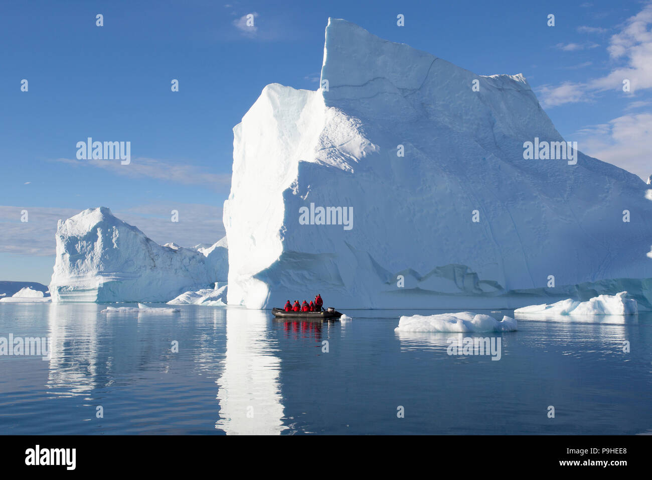 Zodiacs füllen mit Touristen Schwimmer unter enormen Eisberge in Scoresby-sund, Grönland Stockfoto