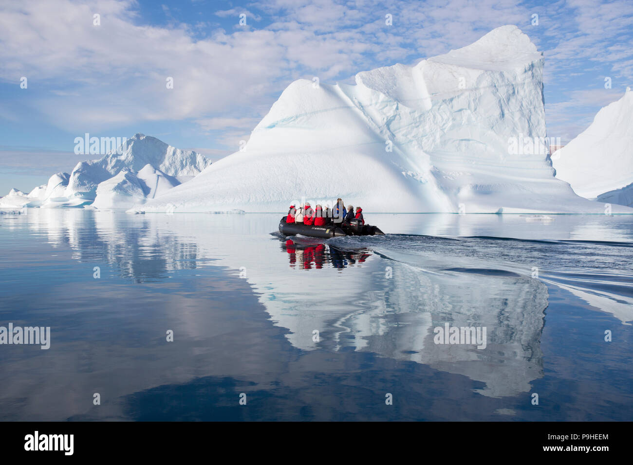 Zodiacs füllen mit Touristen Schwimmer unter enormen Eisberge in Scoresby-sund, Grönland Stockfoto