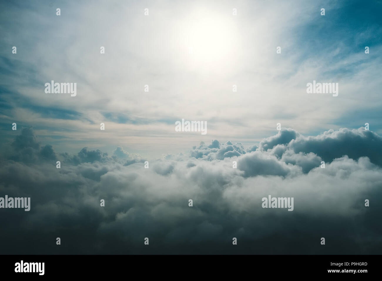 Ein Blick von hoch über den Wolken. Blick auf die Wolken aus dem Fenster des Flugzeugs. Nicht-Flugwetter. Die Sonne strahlt durch das dunkle Blau und gr Stockfoto