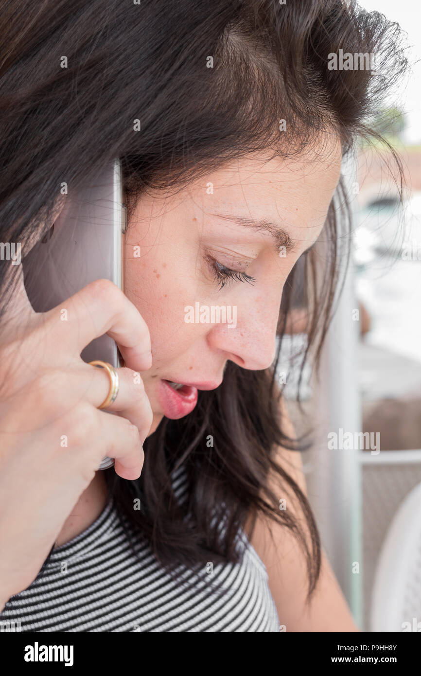 Brunette Mädchen mit einem gestreiften T-Shirt Talk auf dem Handy. Ideal für Konzepte. Stockfoto