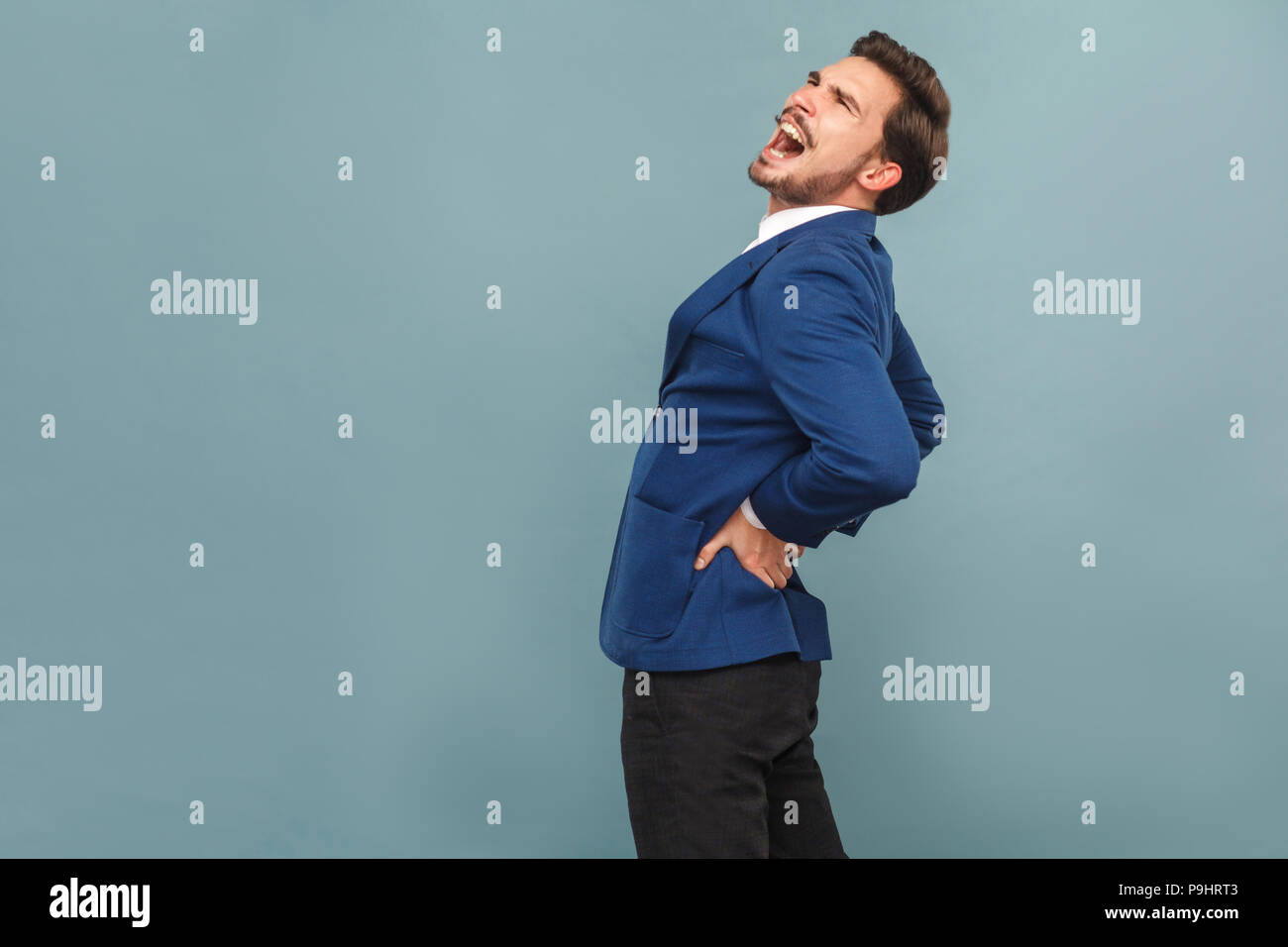 Menschen haben Schmerzen im Rücken. Steine oder Nieren Organe. Portrait von gut aussehenden bärtigen Geschäftsmann in blauen Anzug und weißes Hemd. Innen- studio Shot, isolierte o Stockfoto