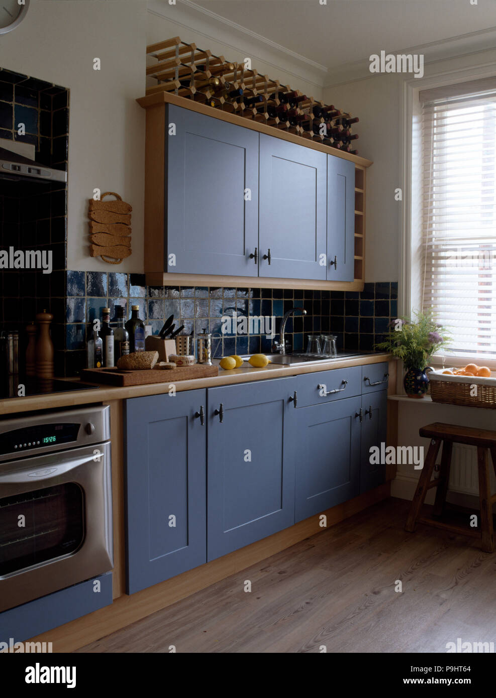 Wine Rack auf blau lackierte Schränke in einem modernen blau-weißen Küche mit Holzböden ausgestattet Stockfoto