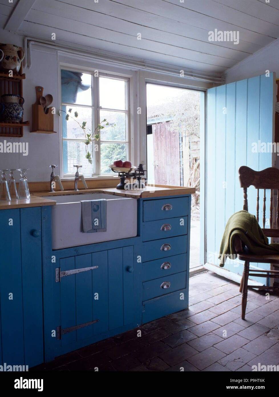 Belfast Waschbecken in Blau ausgestattet Einheit im Cottage Küche mit Backstein Bodenbeläge Stockfoto