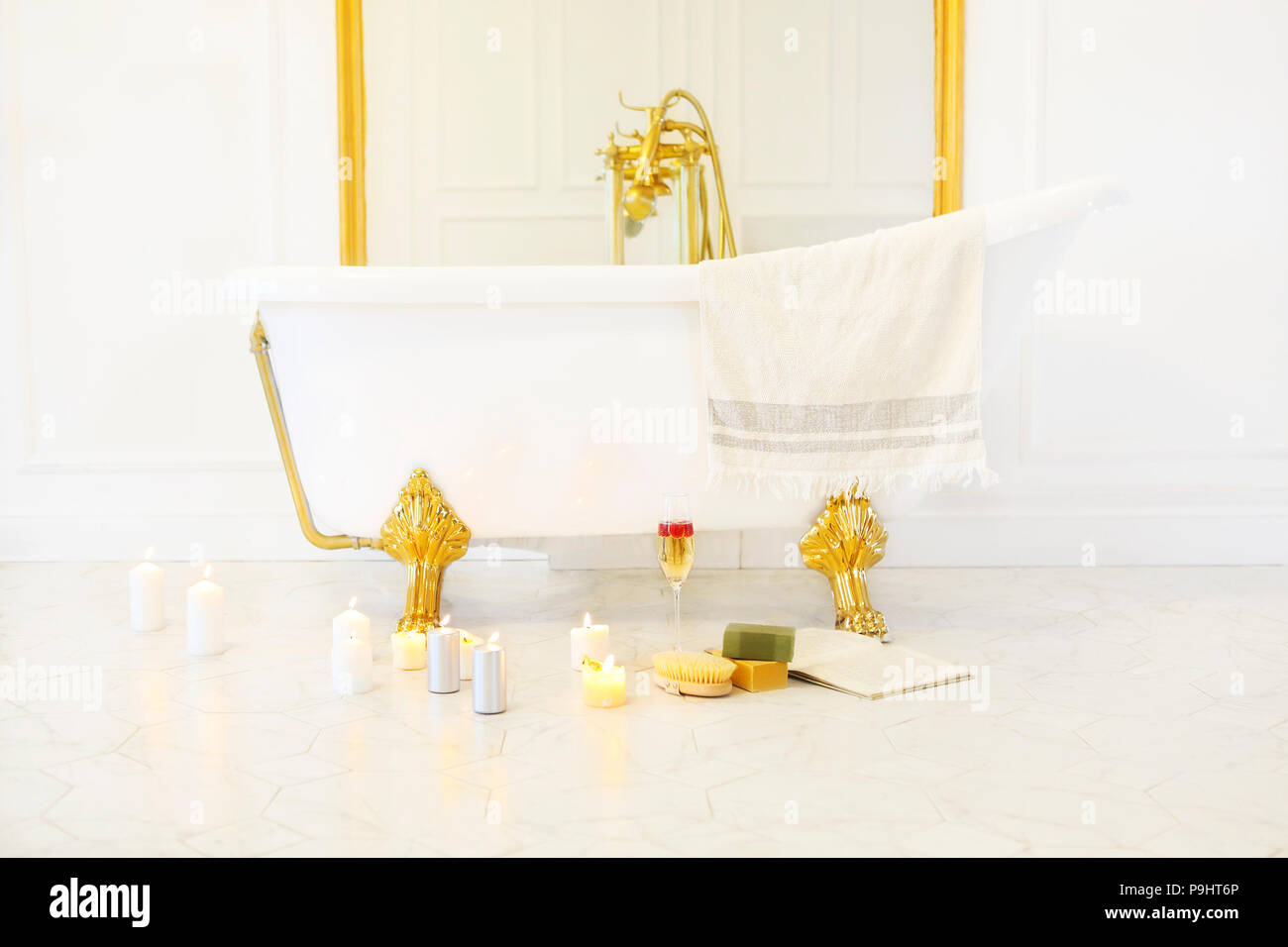 Badezimmer mit Kerzen, einem Buch, einem Glas Champagner in der Badewanne  auf der gefliesten Marmorboden Stockfotografie - Alamy