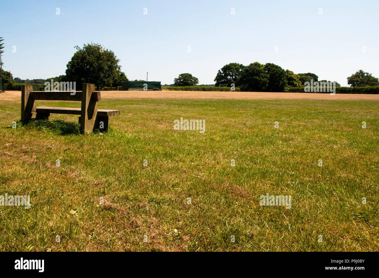 Eine einzelne Bank blickt auf ein leeres Feld. Ein guter Ort, um zu sitzen und zu denken Stockfoto