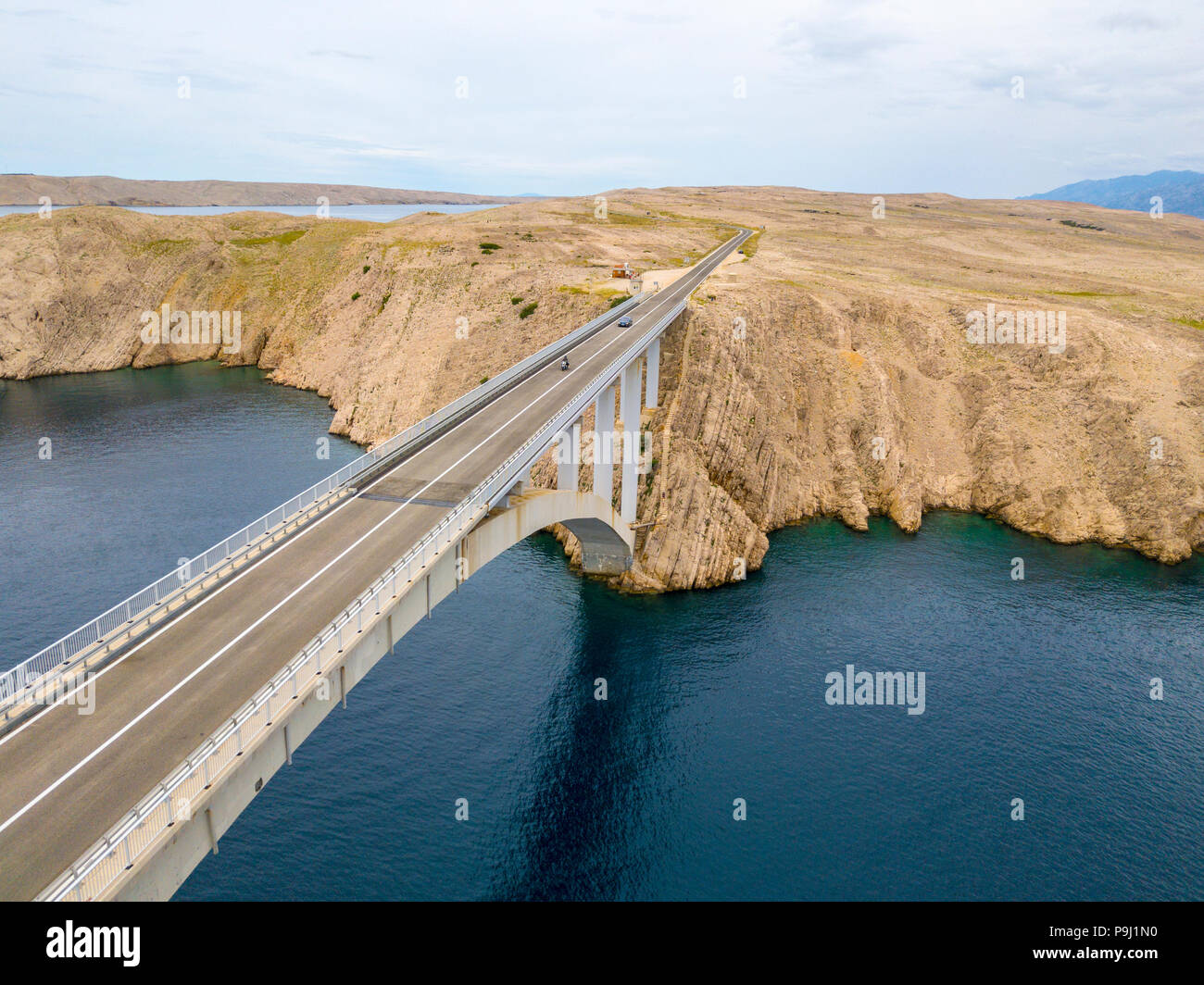 Luftaufnahme der Brücke von der Insel Pag, Kroatien, Straßen und der kroatischen Küste. Klippe mit Blick auf das Meer. Autos über die Brücke von oben gesehen Stockfoto