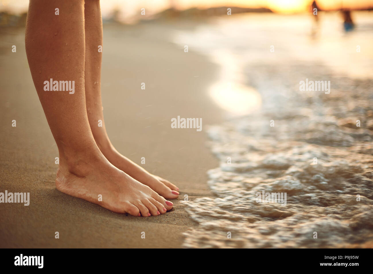 Weibliche Beine am Strand Sand am Meer. Stockfoto