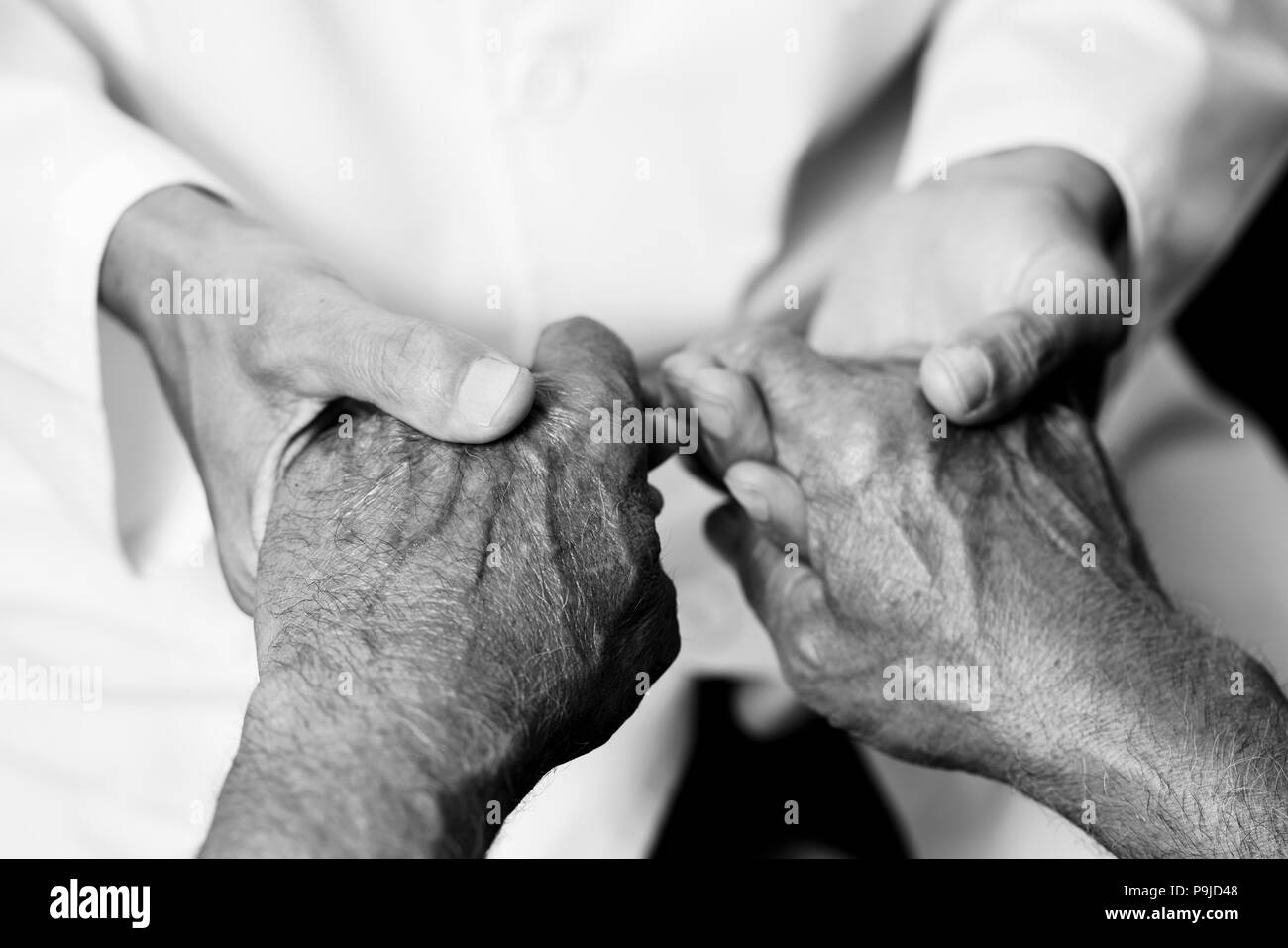 Nahaufnahme von einem kaukasischen Mann, in einem weißen Mantel, an der Hand eines Senior kaukasischen Mann, in Schwarz und Weiß Stockfoto
