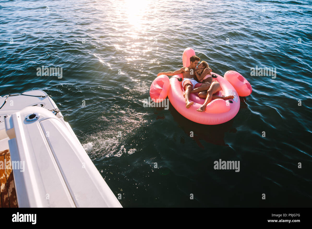 Romantische junge Paar entspannende auf aufblasbaren Top im Meer mit einer Yacht gebunden. Mann und Frau im Sommerurlaub genießen. Stockfoto