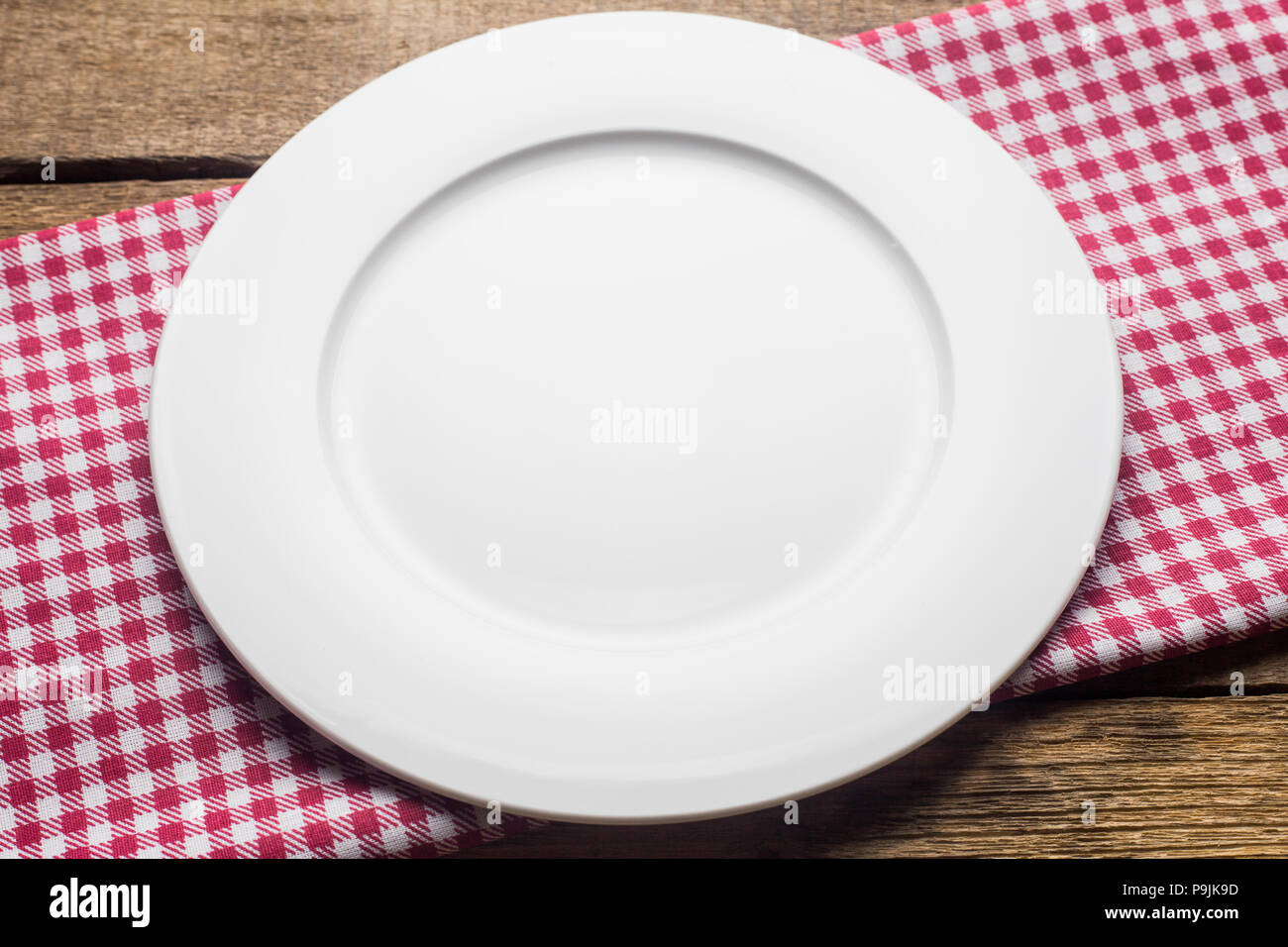 Leeren Teller auf einem hölzernen Hintergrund, eine Serviette in einem Rot und Weiß Stockfoto