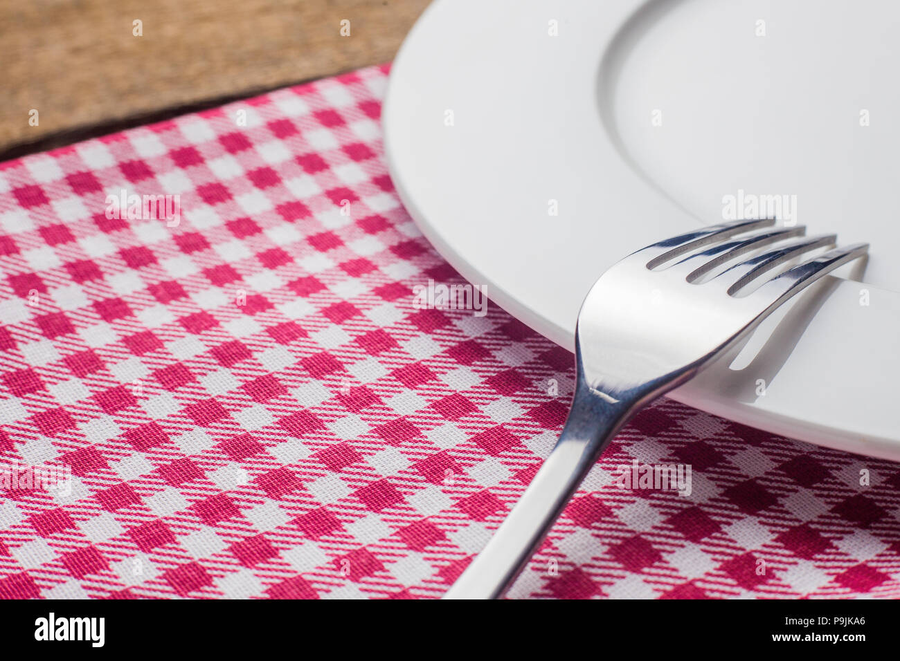 Leeren Teller auf einem hölzernen Hintergrund, eine Serviette in einem Rot und Weiß Stockfoto