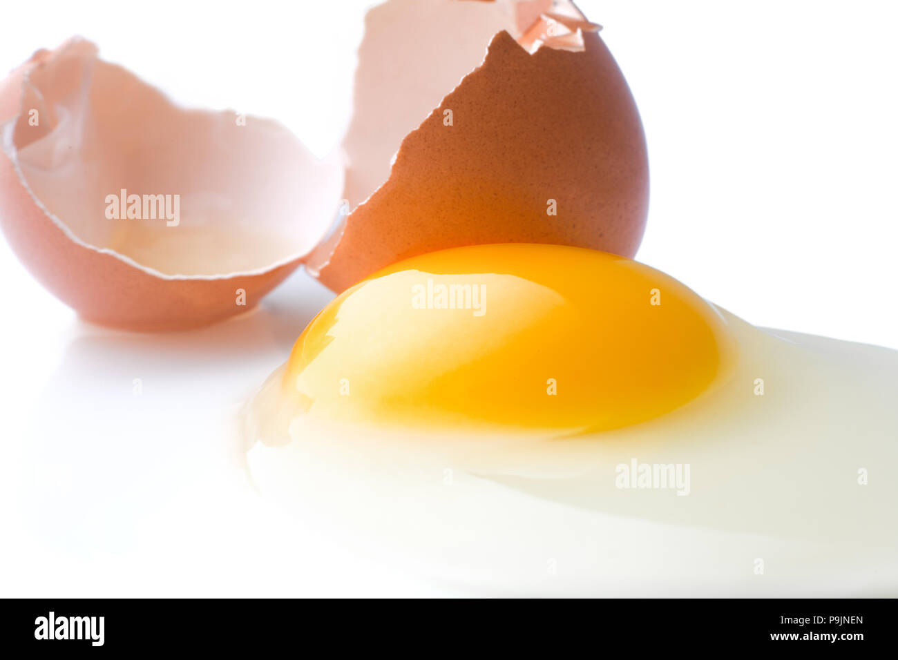 Gebrochene Huhn Ei liegt auf einem weißen Hintergrund mit einer Schale, Eigelb und verschüttete Protein, isoliert Stockfoto