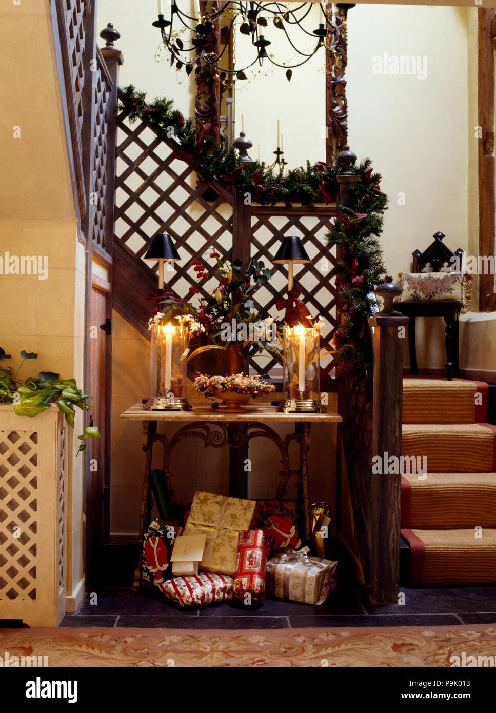 Geschenk verpackt Weihnachtsgeschenke unter kleiner Tisch mit brennenden Kerzen in einem Ferienhaus Halle für Weihnachten dekoriert Stockfoto