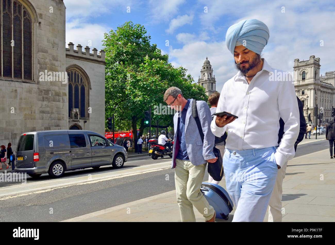 Sikh Mann mit dem Turban (Dastaar/pagri/pagg) und mit Blick auf sein Handy, Central London, England, UK. Stockfoto