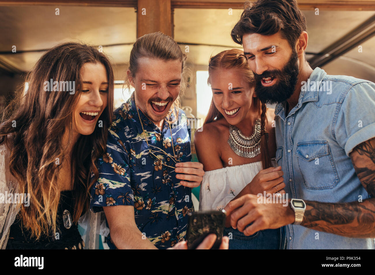 Fröhlicher junger Freunde auf der Suche nach Handy für eine selfie. Gruppe von Männern und Frauen, die selfie im Freien. Stockfoto