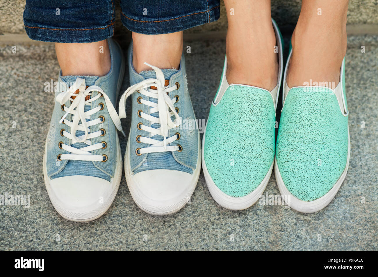 Zwei Paare der Girl's Füße in Turnschuhen Stockfoto