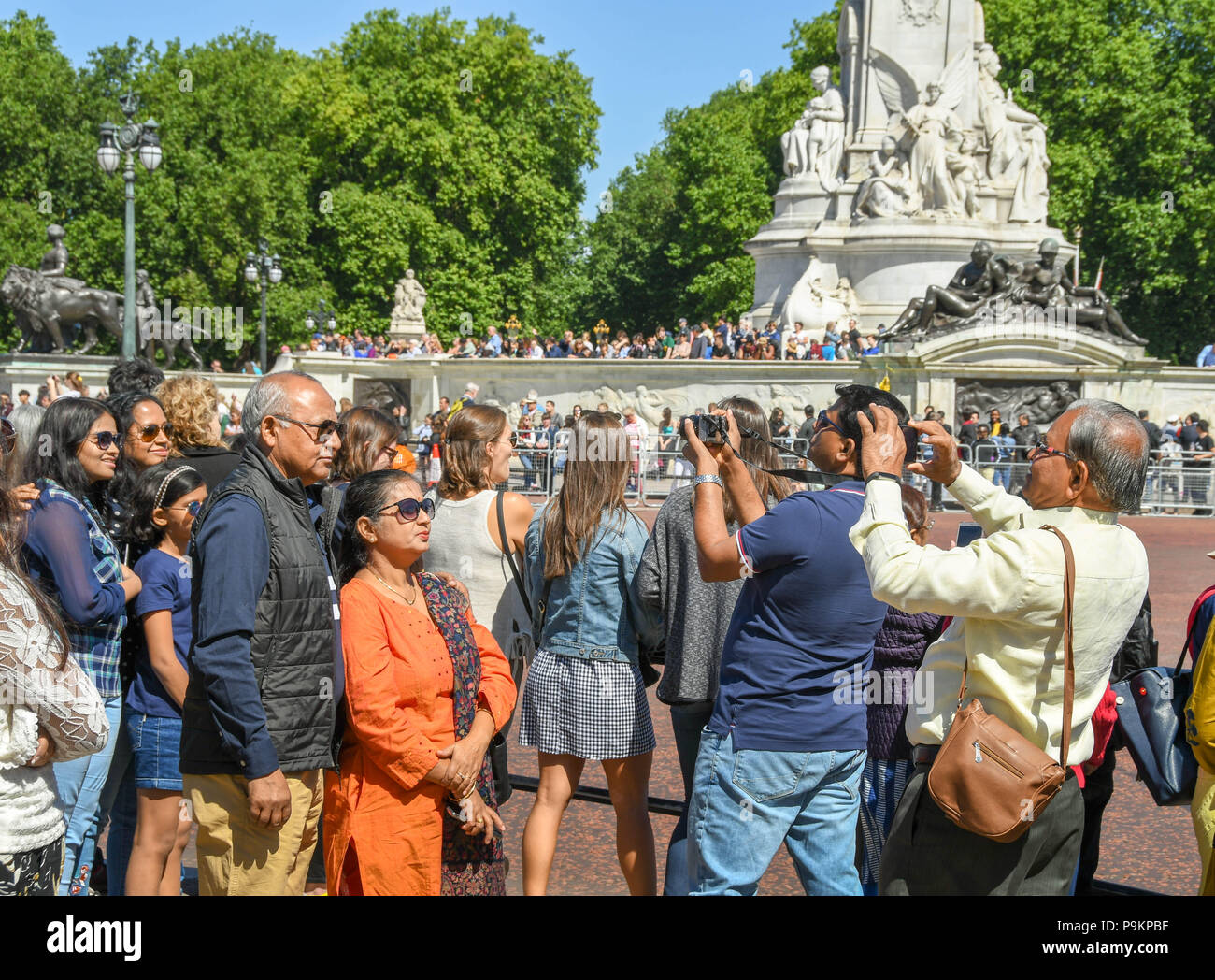 Touristen, die Bilder von anderen Menschen in Ihrer tour Partei außerhalb Buckingham Place Stockfoto