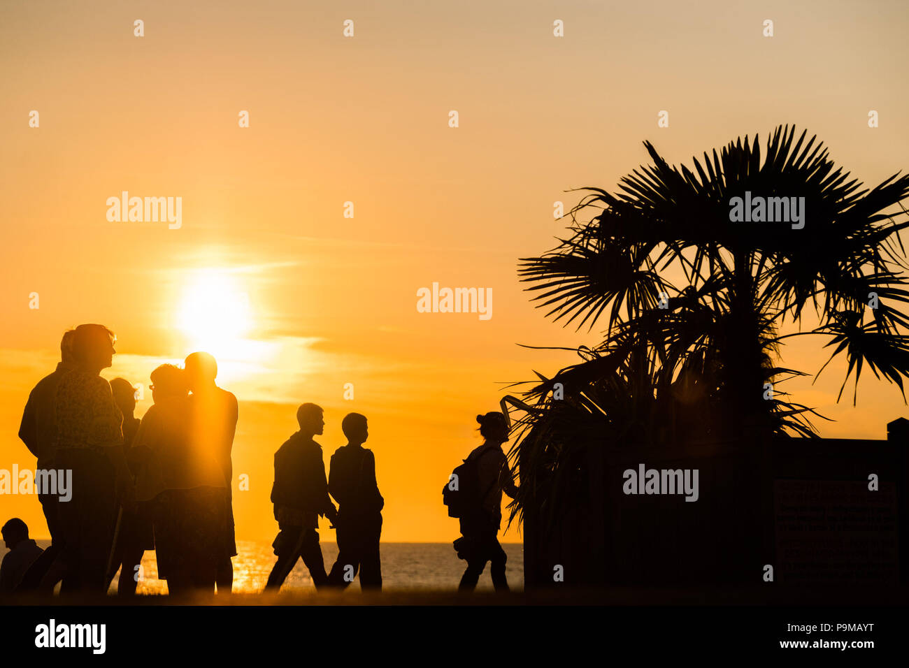 Aberystwyth Wales UK, Donnerstag, 19. Juli 2018 UK Wetter: Menschen sind wie der Spaziergang entlang der Promenade bei Sonnenuntergang in Aberystwyth an der Westküste von Wales. Die Hitzewelle ist so eingestellt, dass es weiter, mit Temperaturen erwartet 30°C wieder bis Ende der Woche Foto: Keith Morris Credit: Keith Morris/Alamy leben Nachrichten Stockfoto