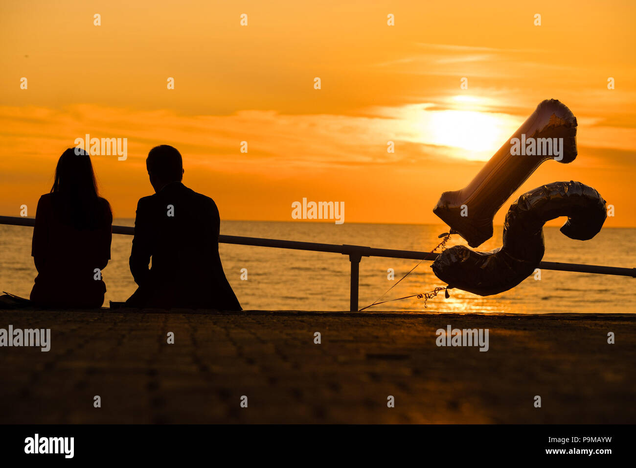 Aberystwyth Wales UK, Donnerstag, 19. Juli 2018 UK Wetter: Menschen sind ab, da sie einen 21. Geburtstag sitzen auf der Promenade bei Sonnenuntergang in Aberystwyth an der Westküste von Wales feiern. Die Hitzewelle ist so eingestellt, dass es weiter, mit Temperaturen erwartet 30°C wieder bis Ende der Woche Foto: Keith Morris Credit: Keith Morris/Alamy leben Nachrichten Stockfoto