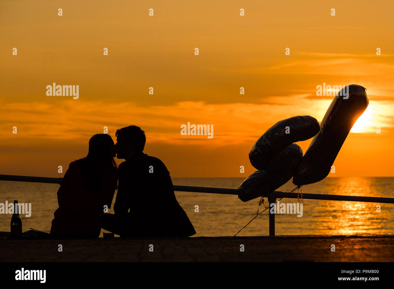 Aberystwyth Wales UK, Donnerstag, 19. Juli 2018 UK Wetter: Menschen sind ab, da sie einen 21. Geburtstag sitzen auf der Promenade bei Sonnenuntergang in Aberystwyth an der Westküste von Wales feiern. Die Hitzewelle ist so eingestellt, dass es weiter, mit Temperaturen erwartet 30°C wieder bis Ende der Woche Foto: Keith Morris Credit: Keith Morris/Alamy leben Nachrichten Stockfoto