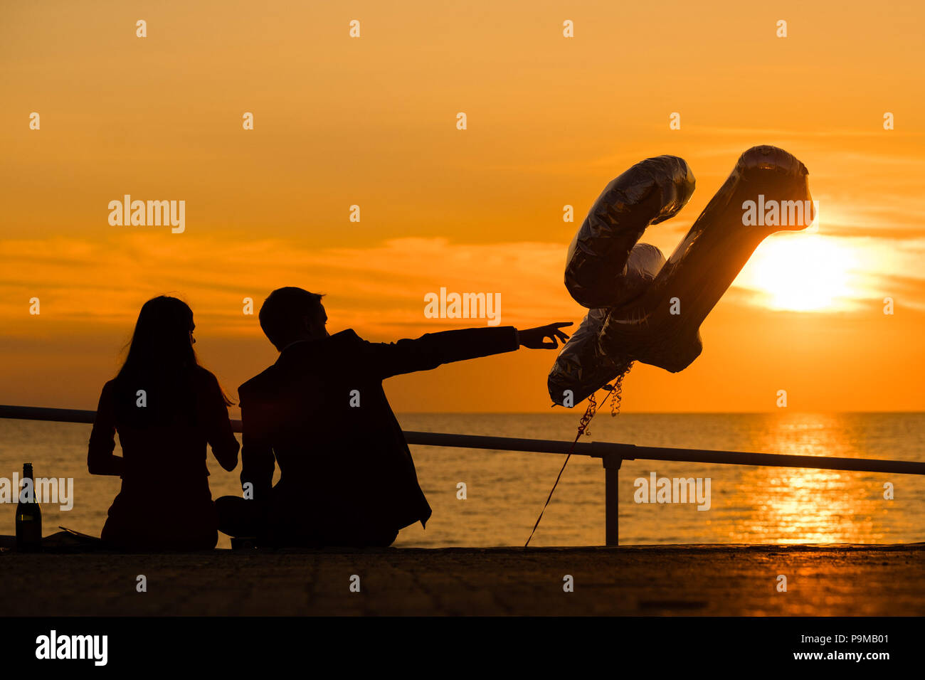 Aberystwyth Wales UK, Donnerstag, 19. Juli 2018 UK Wetter: Menschen sind ab, da sie einen 21. Geburtstag sitzen auf der Promenade bei Sonnenuntergang in Aberystwyth an der Westküste von Wales feiern. Die Hitzewelle ist so eingestellt, dass es weiter, mit Temperaturen erwartet 30°C wieder bis Ende der Woche Foto: Keith Morris Credit: Keith Morris/Alamy leben Nachrichten Stockfoto