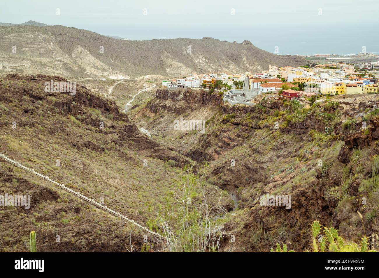 Blick auf den Barranco del Infierno (Hell's Gorge), das Tal oder Canyon mit der Stadt Adeje oben mit hellen, freundlichen Gebäuden, Atlantik, grün Stockfoto