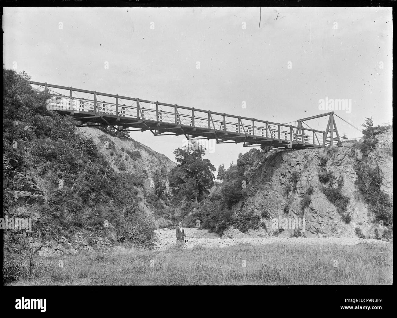 332 Frau (wahrscheinlich der Fotografin Frau Laura Godber) Holding ein Billy beim Stehen auf der Steinernen Bank von einem Strom, unter einer Hängebrücke ATLIB 312416 Stockfoto