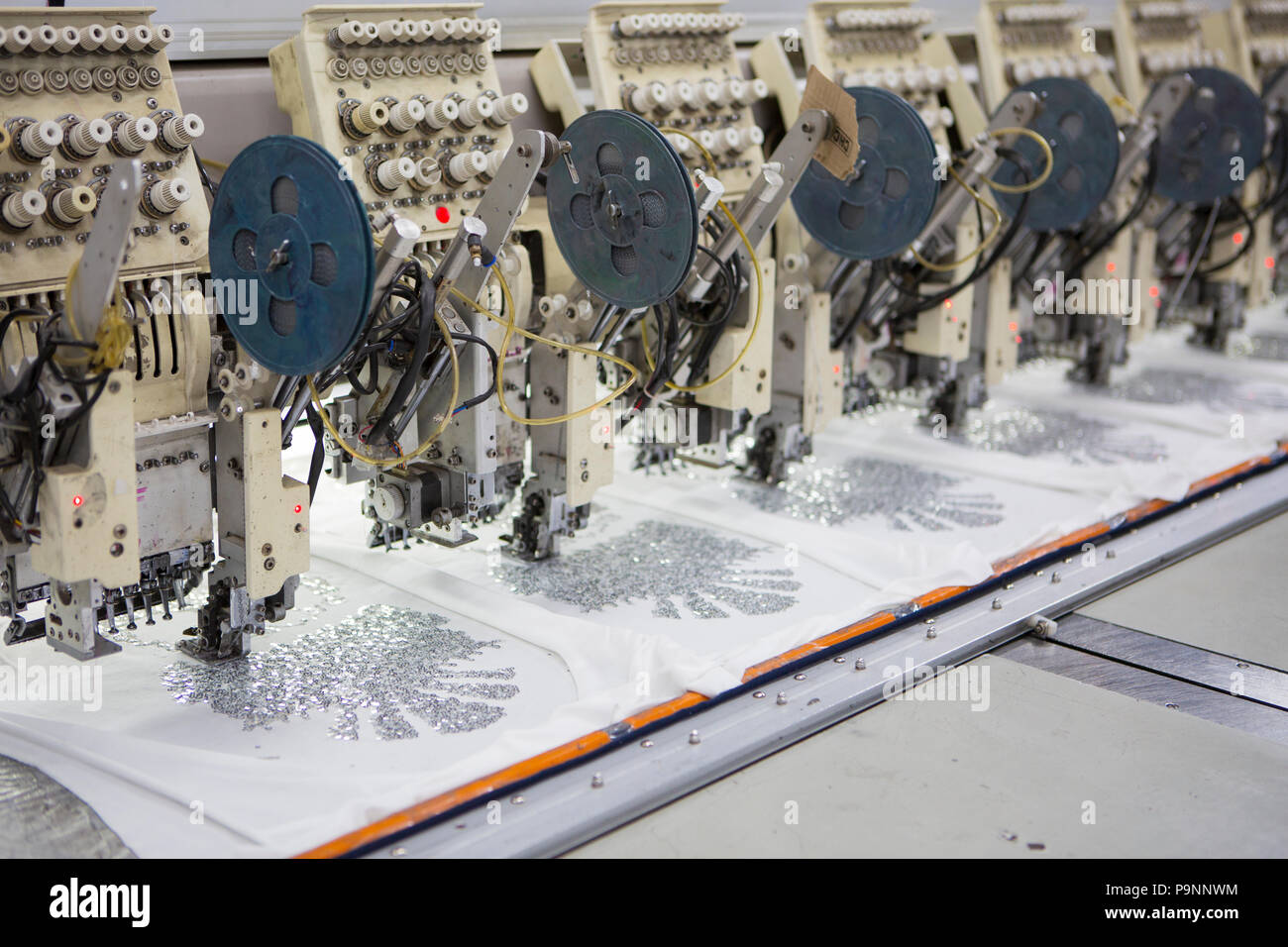 Nähmaschinen, drucken Sie eine Pailletten Design auf einem bio Baumwoll-T-Shirt in einer Fabrik, wo organische Baumwolle verwendet wird Kleidung zu machen, Indore, Indien. Stockfoto
