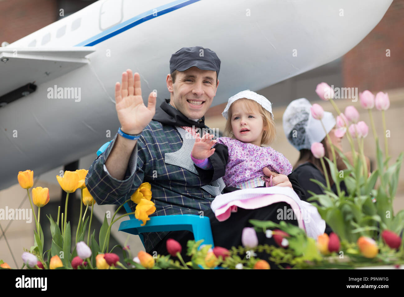 Holland, Michigan, USA - 12. Mai 2018, Vater und Tochter, die traditionelle niederländische Kleidung winken in die Kamera von Tulip Blumen am M umgeben Stockfoto