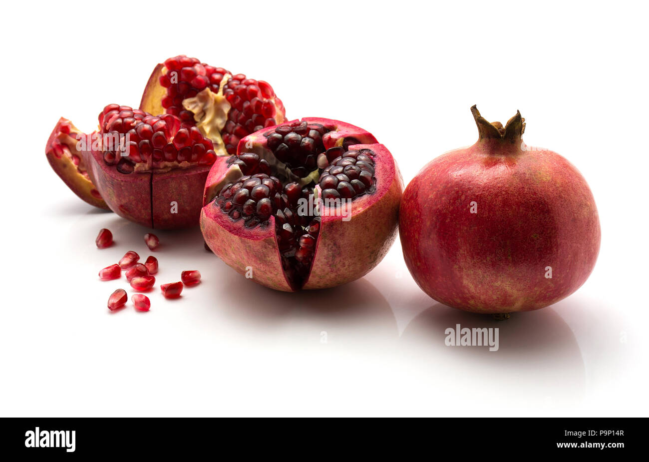Zwei offene Granatapfel mit der geoffenbarten Körner und ein Ganzes auf weißem Hintergrund Stockfoto