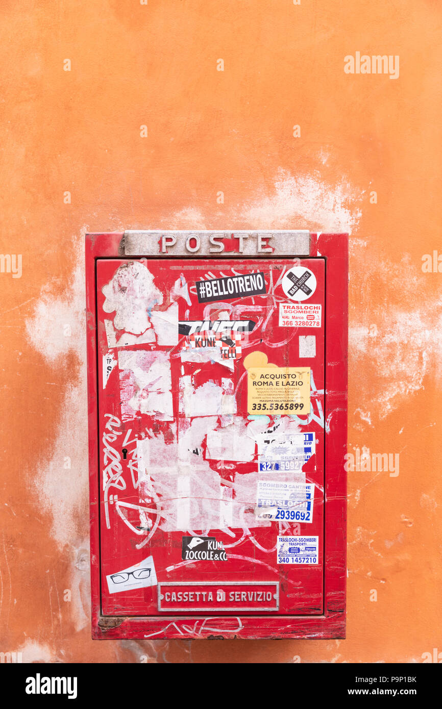 Einen roten Briefkasten auf eine orange Pflasterwand in Rom, Italien. Stockfoto