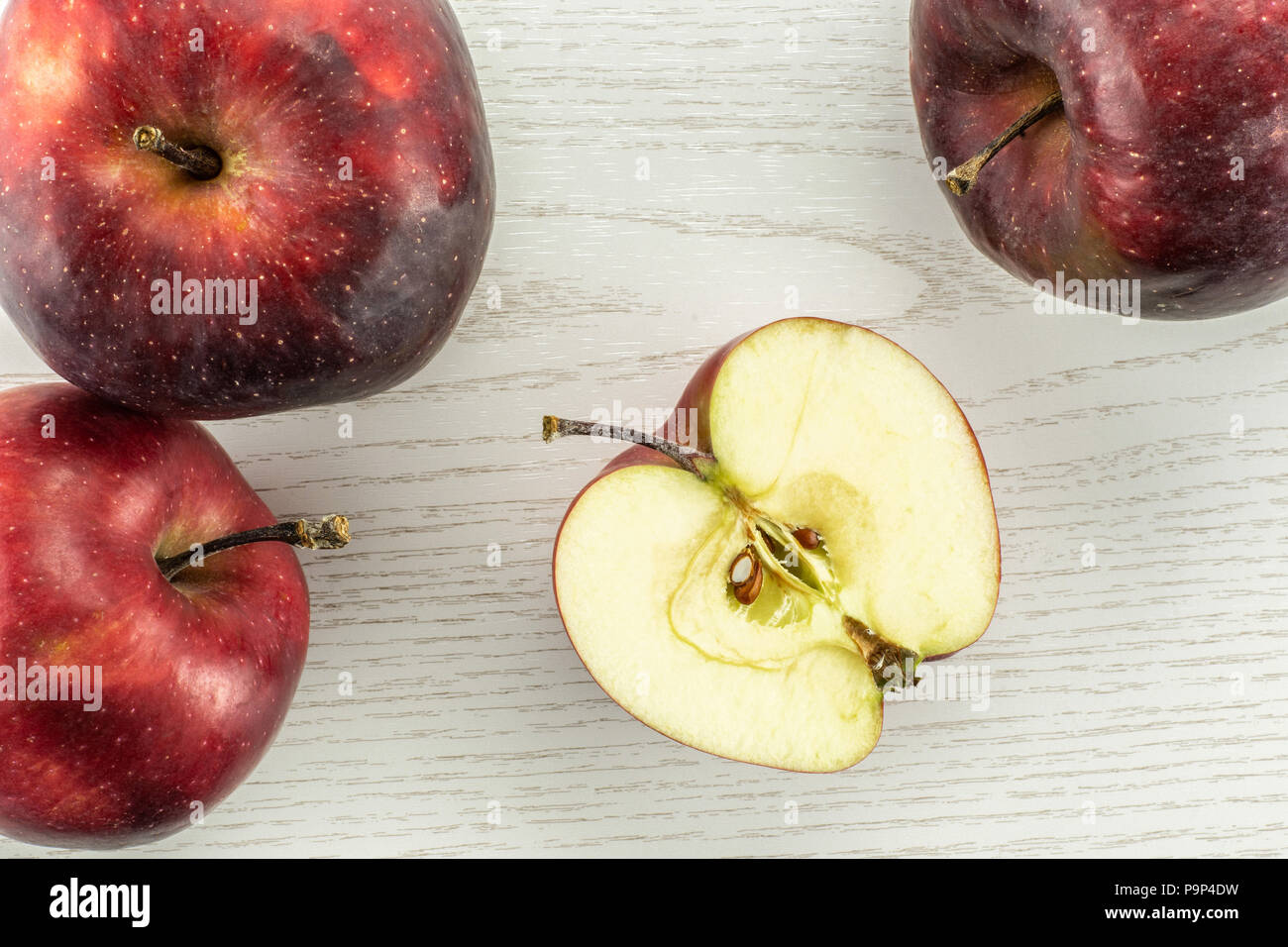 Red Delicious drei Äpfel und eine Hälfte flatlay auf grau Holz Hintergrund Stockfoto
