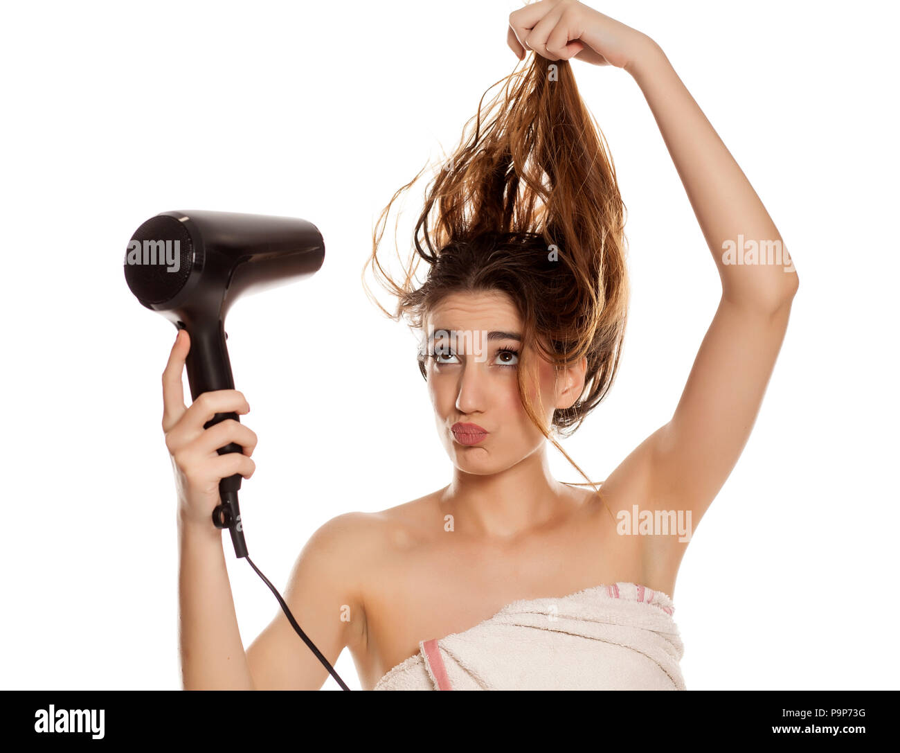 Junge schöne Frau, die ihre Haare trocknen mit einem Fön auf weißem Hintergrund Stockfoto