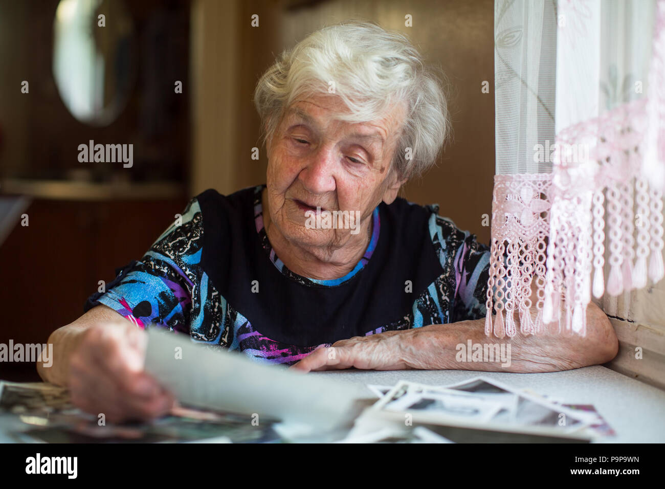 Ältere Frau ansehen Fotos bei Tisch sitzen. Stockfoto