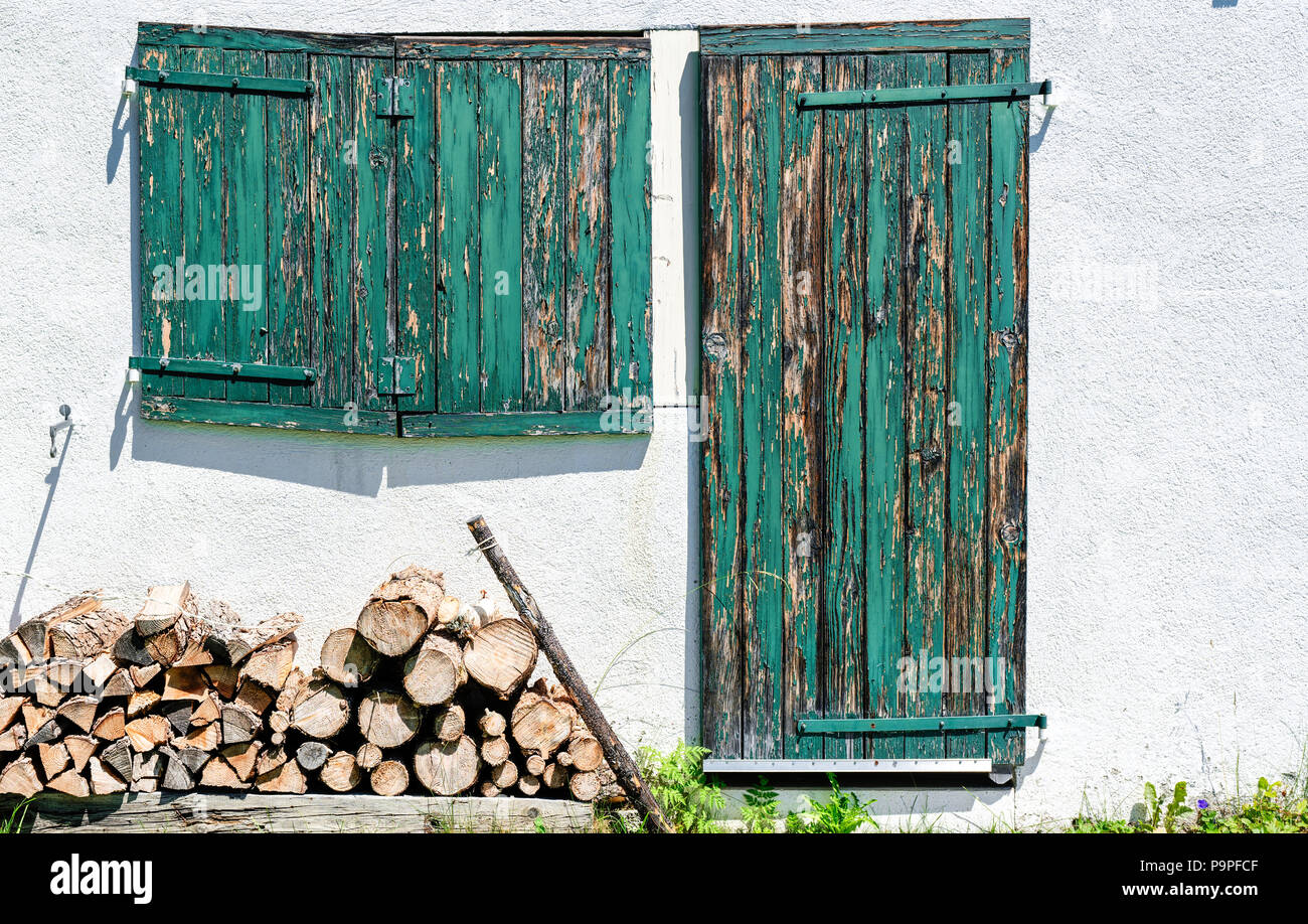 Von einem Haus in der Nähe der Vorderseite mit rustikalen Holzmöbeln grünen Fensterläden und Türen und Brennholz Stockfoto