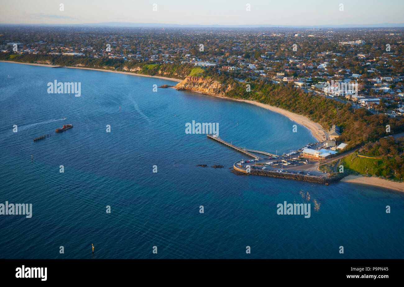 Ariel Blick auf Blackrock Strand, Felswand, lifesaving Club, Pier und Laderampe mit Melbourne City in der Ferne. Stockfoto