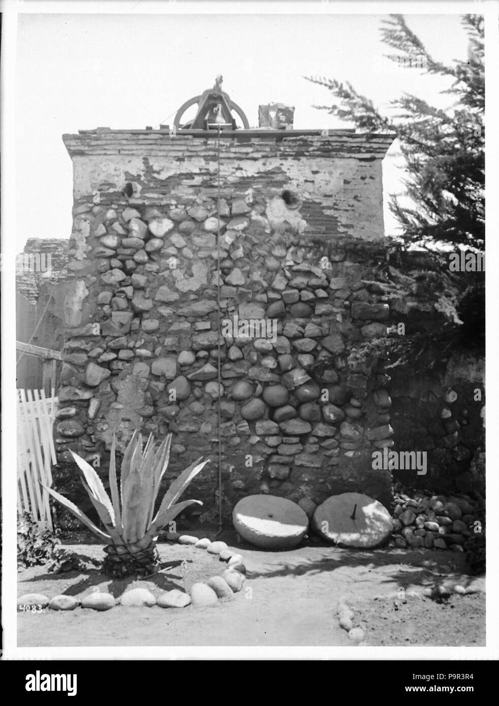 . Englisch: Glockenturm San Diego Mission, Ca. 1905 Foto der Glockenturm von San Diego Mission, Ca. 1905. Ein Seil an der Glocke angebracht (s) hängt von der Halterung oben am Turm aus Naturstein. Zwei stillgelegte Mühle lag auf dem Boden am Fuße des Turms in der Nähe von einem gepflegten Yucca Pflanze, die in einem Halbkreis von Steinen wächst. Teil einer weissen Lattenzaun ist auf der linken Seite sichtbar. Rufnummer: CHS-4083 Legacy Datensatz-ID: CHS-m 16591; USC-1-1 -1-14081 Fotograf: James, George Wharton Dateiname: CHS-4083 Abdeckung Datum: ca. 1905 Teil der Sammlung: California Historical Society Col Stockfoto