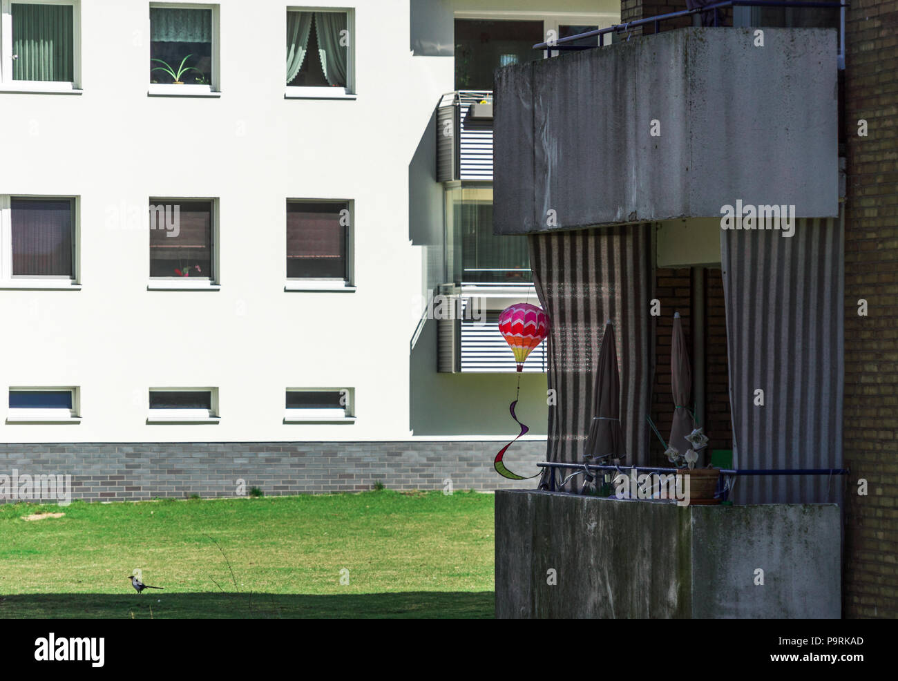 Schattig dunkle Siedlung mit Reihenhäusern in einem Vorort, mit einem farbenfrohen Spielzeug Ballon auf ein hässliches schmutzige alte Balkon, Vorort Stockfoto