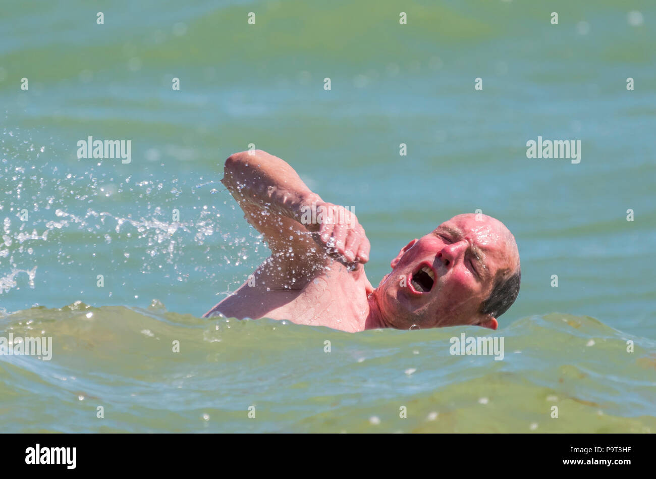 Mann Schwimmen im Meer in Großbritannien mit seinem Kopf aus dem Wasser Nehmen eines Atems. Mann Schwimmen im Ozean. Stockfoto