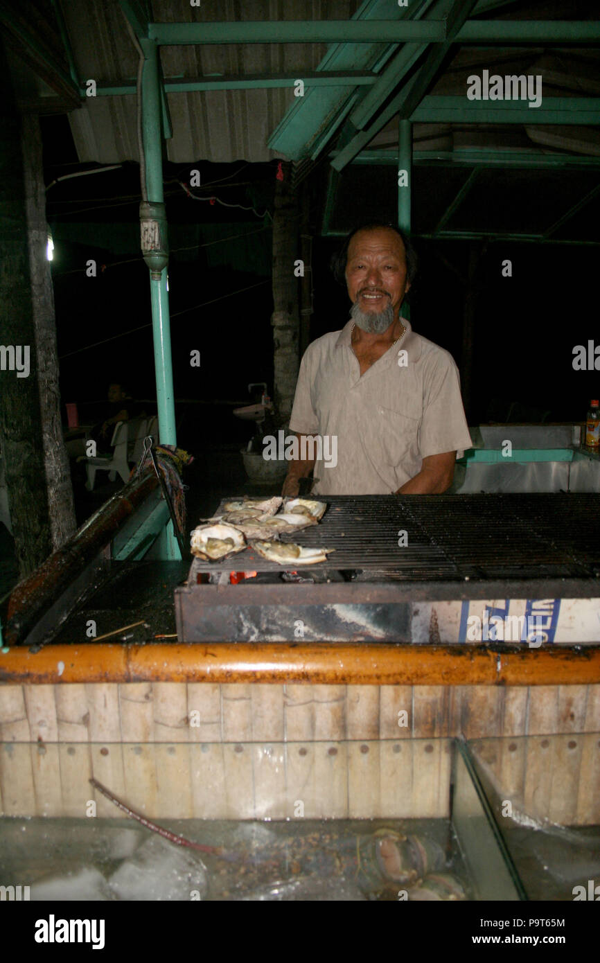 Vietnamesische Mann Kochen Meeresfrüchte vom Grill in der Straße ausgeht, Mui Ne, Vietnam Stockfoto