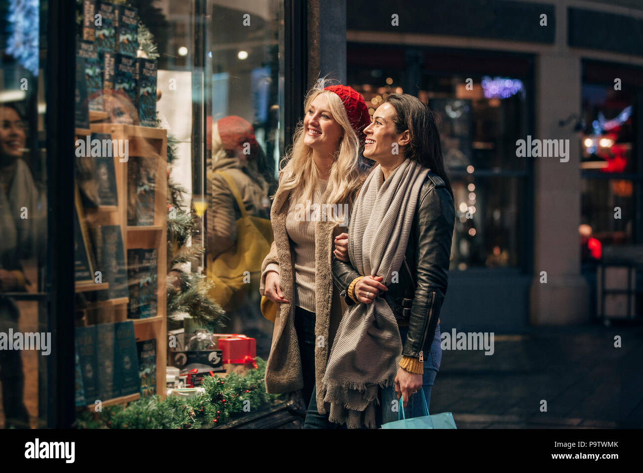Seitliche Sicht auf zwei erwachsene Frauen, die in einem Schaufenster, während Sie ein paar Weihnachtseinkäufe. Stockfoto