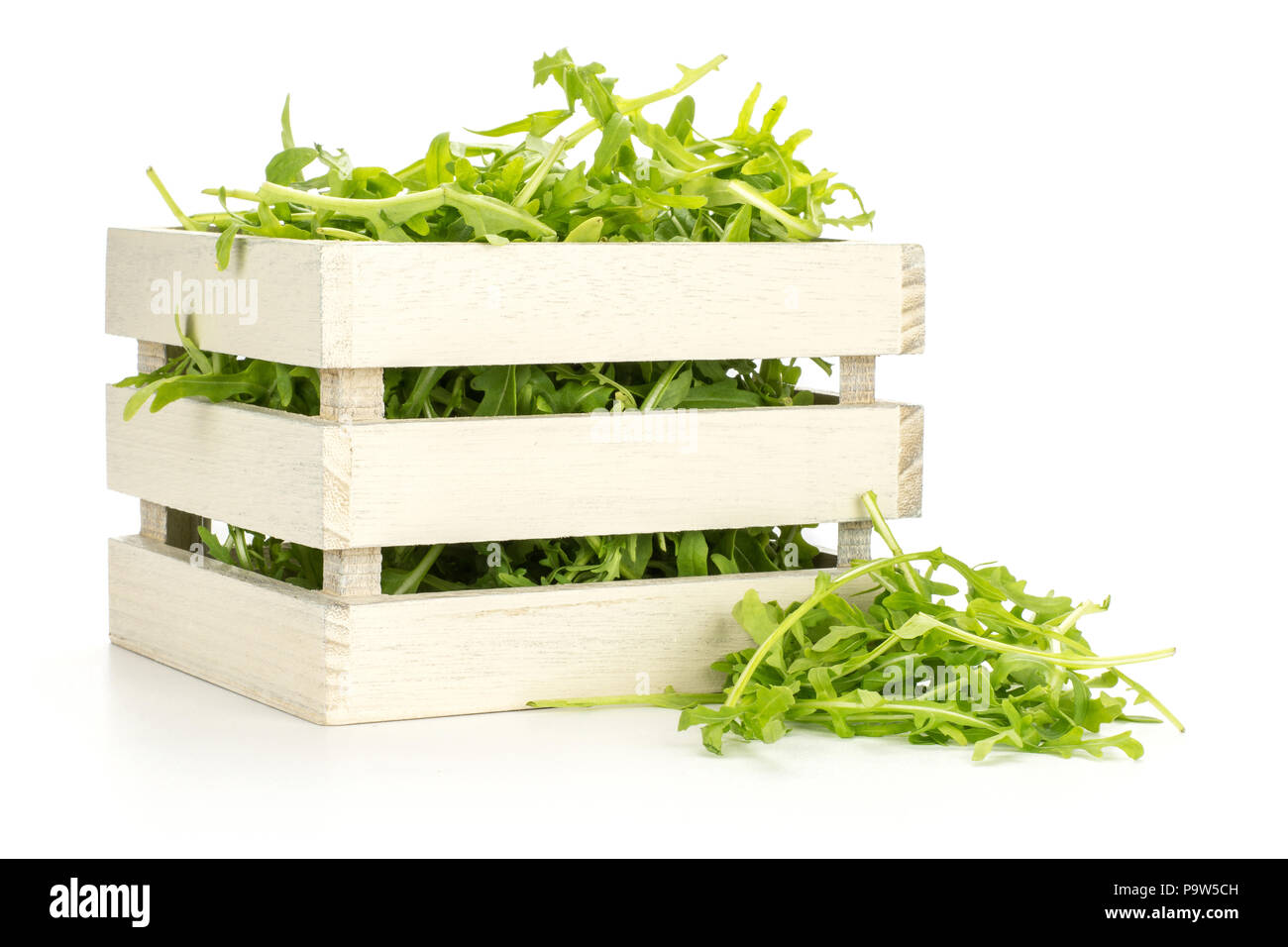 Frische Rucola Blätter in einer Holzkiste auf weißem Hintergrund Stockfoto