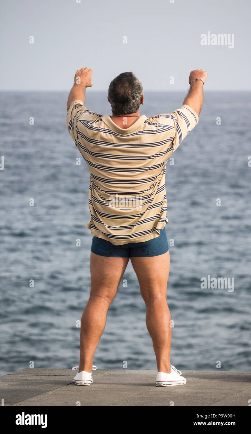 Ansicht der Rückseite des reifer Mann Durchführen von Tai Chi mit Blick auf das Meer Stockfoto