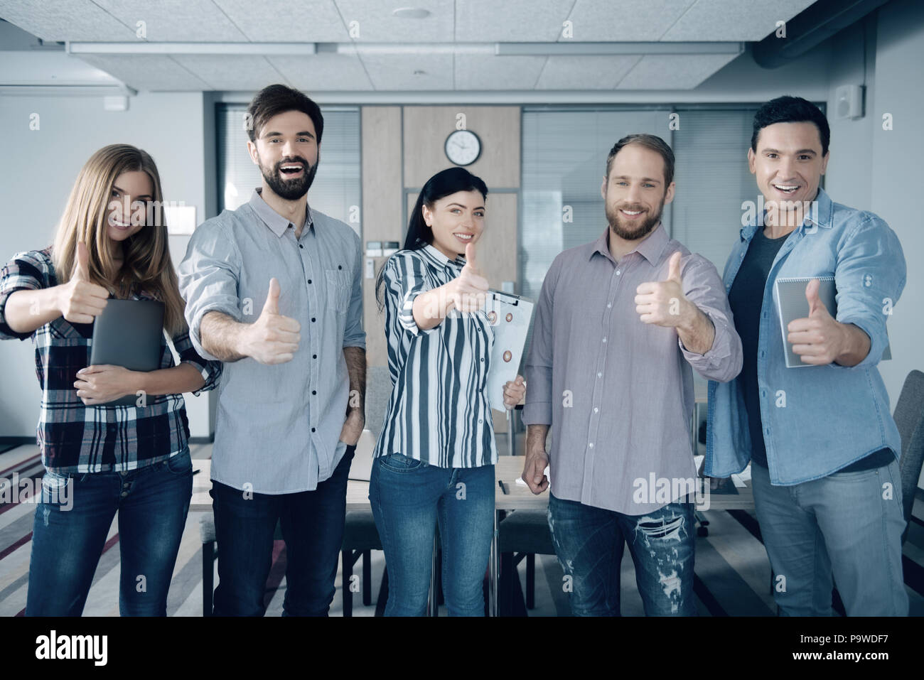 Jeden Tag genießen. Gruppe von fröhlichen jungen Kollegen abgreifen und ständigen im Büro Stockfoto
