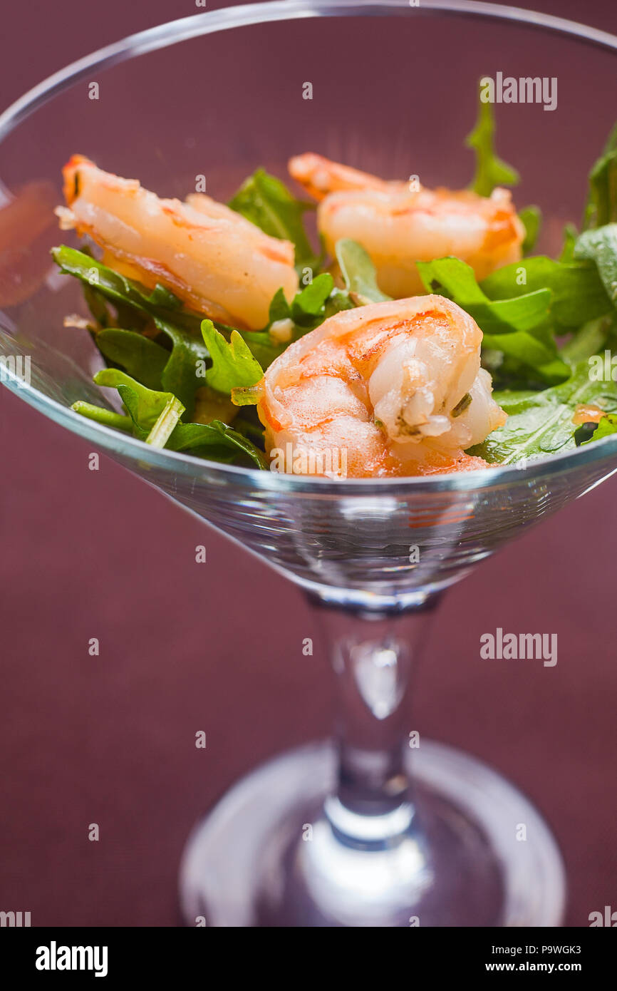 Salat aus Rucola, Garnelen, Pinienkerne, in ein Glas Kosten auf einer Ta Stockfoto