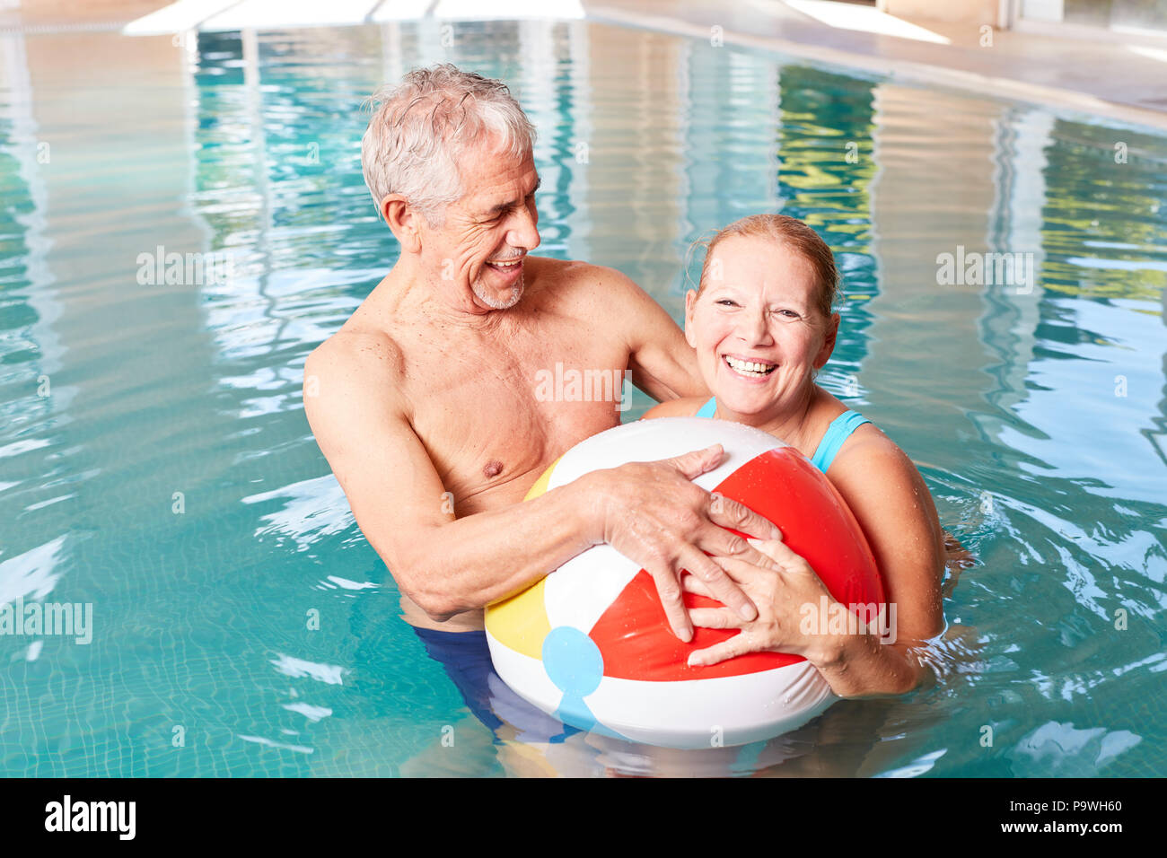 Senior Paar hat Spaß mit einem Wasserball im Pool einen Wellnessurlaub Stockfoto