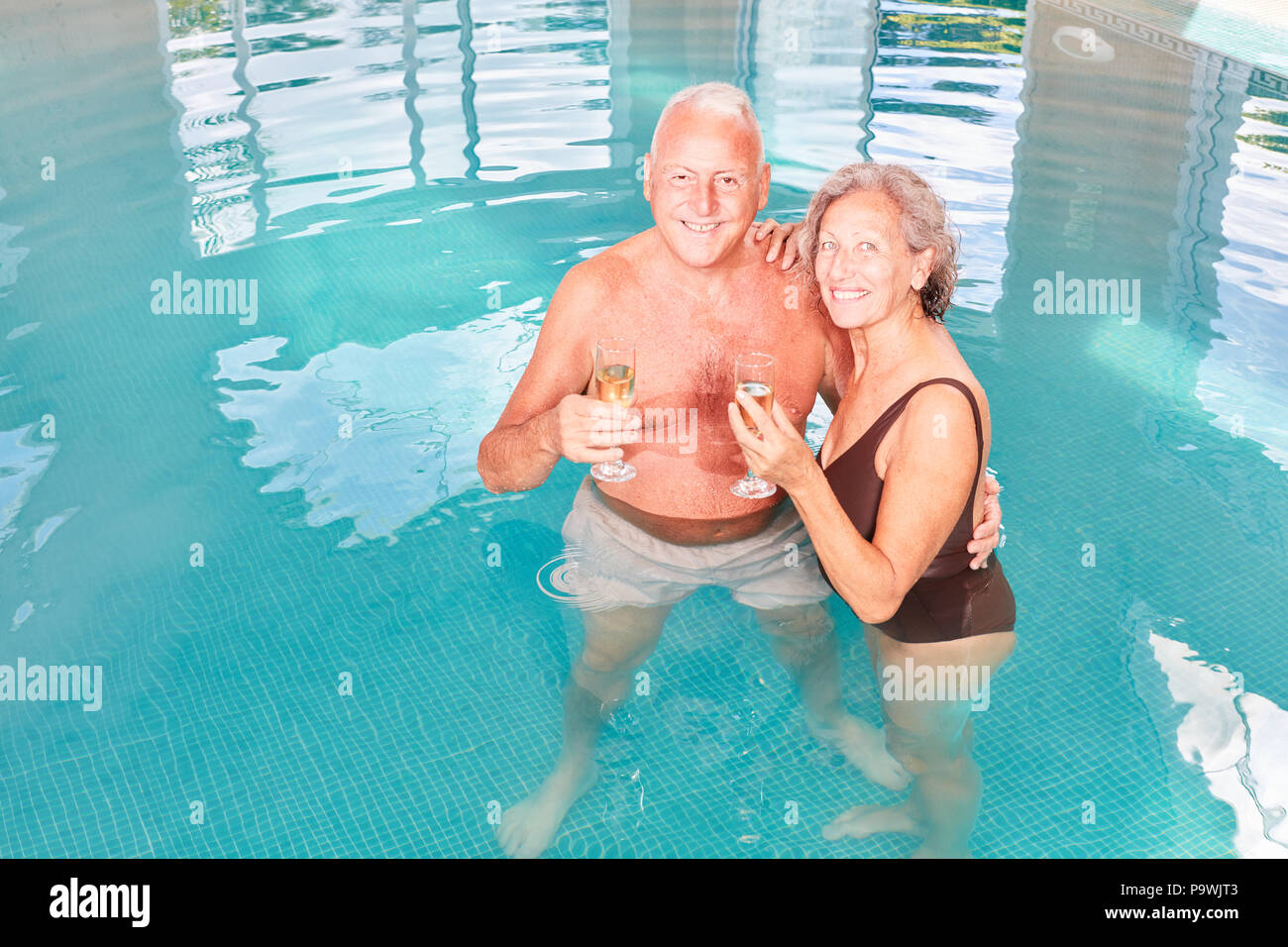 Happy Senioren Paar feiert mit Sekt im Schwimmbad im Wellness Hotel Stockfoto