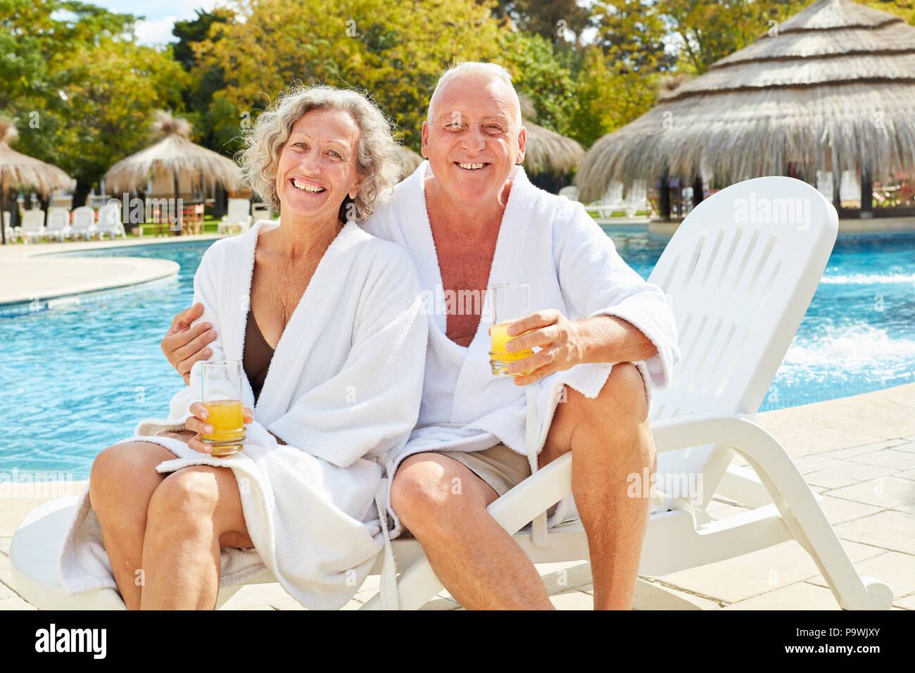 Gerne älteres Paar in Spa Urlaub am Pool mit Orangensaft Stockfoto